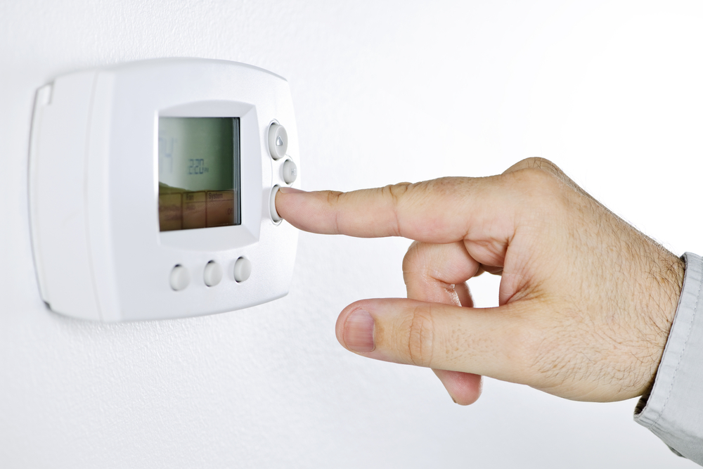 Man programming thermostat to save energy