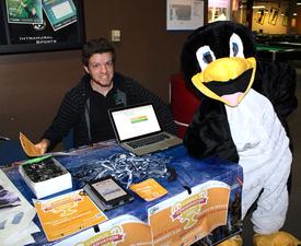 Cal Poly Pomona intern Brandon Sauer posing with another intern wearing the team's PowerSave mascot, Penny the Penguin, during a tabling event for a national energy savings competition called Campus Conservation Nationals (CCN) Cal Poly Pomona intern Brandon Sauer posing with another intern wearing the team's PowerSave mascot, Penny the Penguin, during a tabling event for a national energy savings competition called Campus Conservation Nationals (CCN)