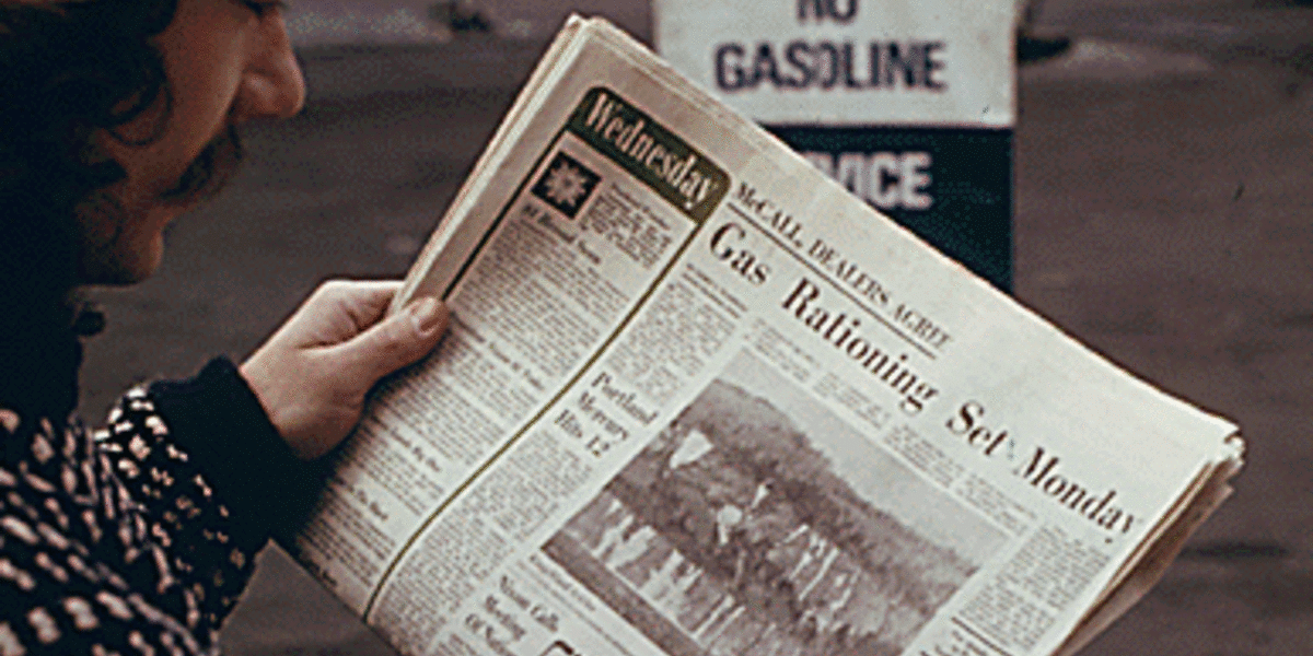 Man reading newspaper article on gas shortage 1973 oil embargo crisis